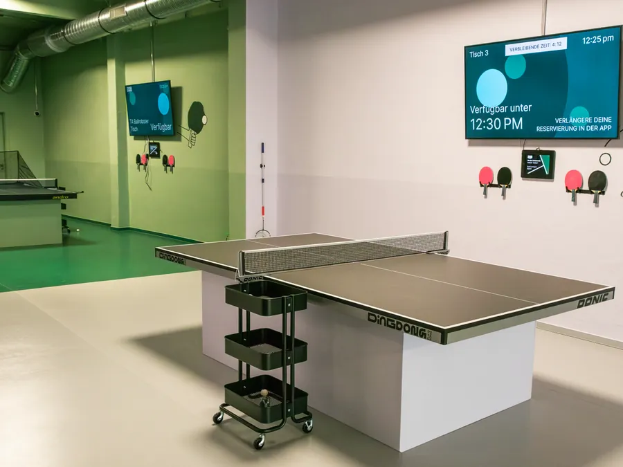Indoor-Tischtennis-Halle mit App-Anzeige bei Ding Dong Ping Pong in Prenzlauer Berg, Berlin – wetterfest spielen bei Regen